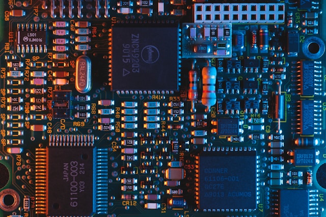 Close-up of a printed circuit board with microchips, capacitors, resistors, and other electronic components connected by fine copper traces.