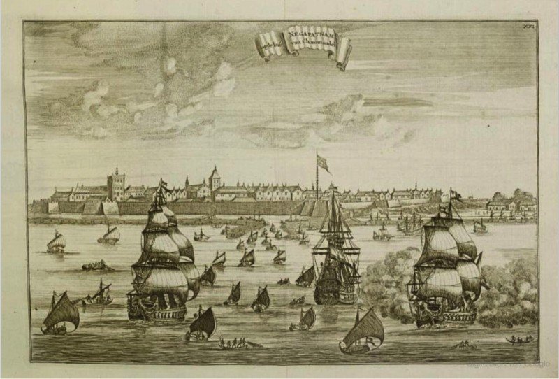 An image of coastline captured from the sea. There are boats and ships on the sea and groynes on the coast. 