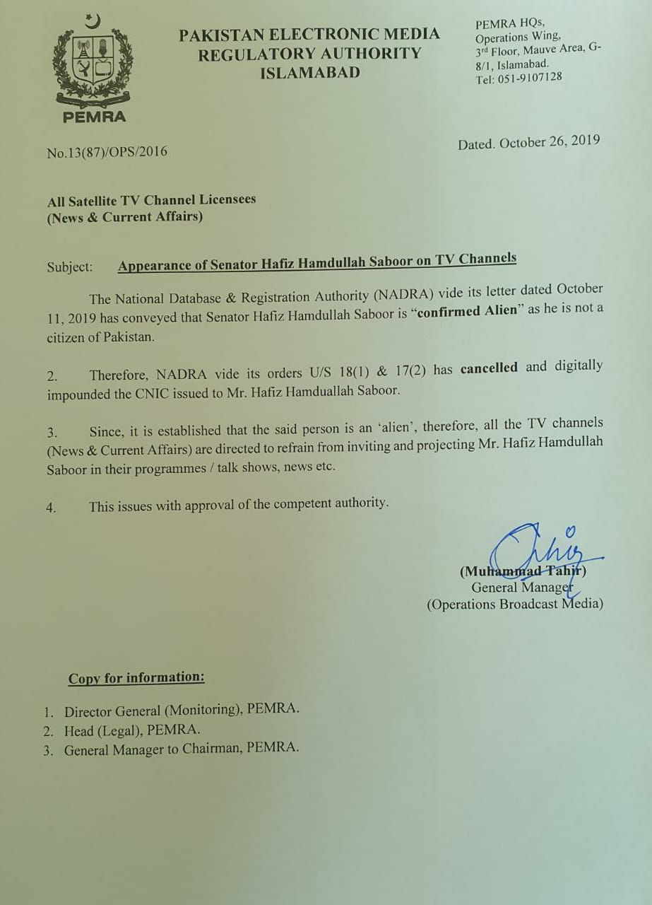 The image is a photograph of a 2019 notification sent by the Pakistan Electronic Media Regulatory Authority (PEMRA), Islamabad, to all satellite TV channel licensees (news and current affairs) and is dated October 26, 2019. On the top left hand corner of the notification is the PEMRA logo consisting of a shield surrounded by a wreath, lying below a star nestled within a crescent moon. On the top right hand corner is the PEMRA headquarters address, noted as Operations Wing, 3rd Floor, Mauve Area, G-8/1 Islamabad, Tel: 051-9107128. The notification number is 13(87)/OPS/2016. The text of the notification is as follows. Subject: Appearance of Senator Hafiz Hamdullah Saboor on TV Channels The National Database and Registration Authority (NADRA) vide its letter dated October 11, 2019 has conveyed that Senator Hafiz Hamdullah Saboor is “confirmed Alien” (quoted text appears in bold) as he is not a citizen of Pakistan. Therefore, NADRA vide its orders U/S 18 (1) and 17 (2) has cancelled (word appears in bold) and digitally impounded the CNIC issued to Mr. Hafiz Hamdullah Saboor. Since, it is established that the said person is an ‘alien,’ therefore all the TV channels (News and Current Affairs) are directed to refrain from inviting and projecting Mr. Hafiz Hamdullah Saboor in their programmes / talk shows, news etc. This issues with approval of the competent authority. After the text in the body of the notification, on the bottom right hand corner is a signature in blue ink by Muhammad Tahir, General Manager, Operations Broadcast Media. Below it, on the bottom left hand corner, is a note with the following text: Copy for information (text appears in bold): Director General (Monitoring), PEMRA, Head (Legal) PEMRA, and General Manager to Chairman, PEMRA.