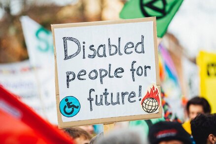 A placard from a climate change protest with "Disabled people for future!" written on it with a small size disability icon on bottom left of the placard and a small size world on fire icon on bottom right of it