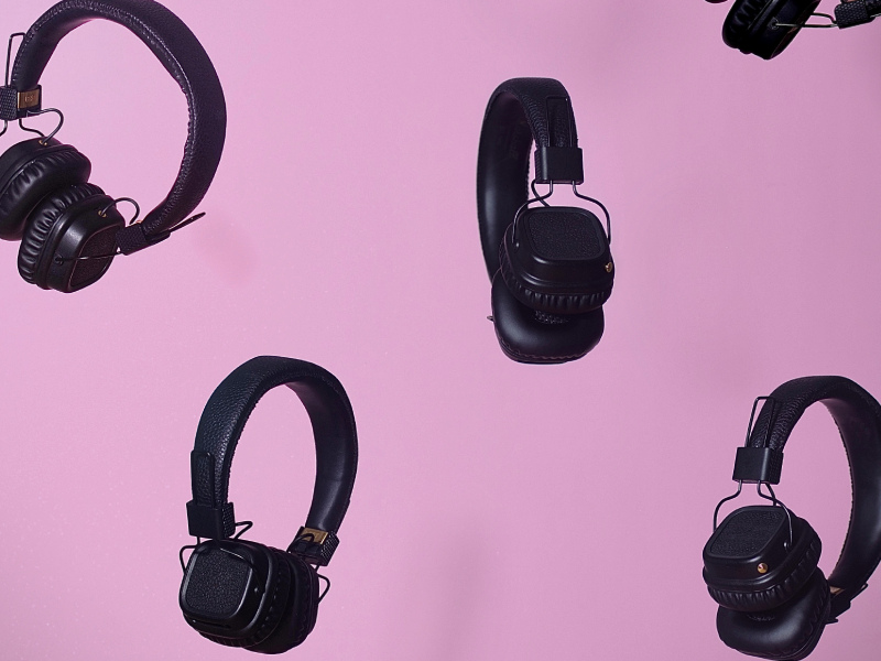 5 headphones floating on a pink wall